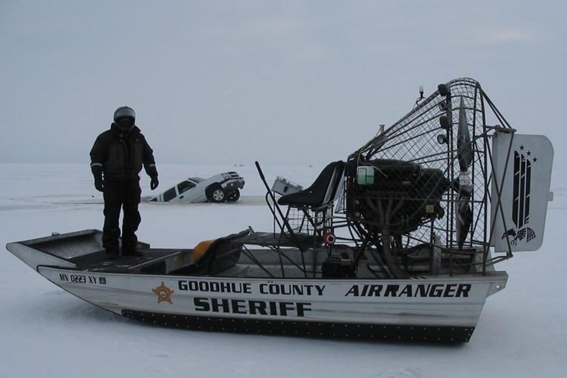 A Goodhue County officer posing on their winter patrol vehicle positioned on the frozen lake.
